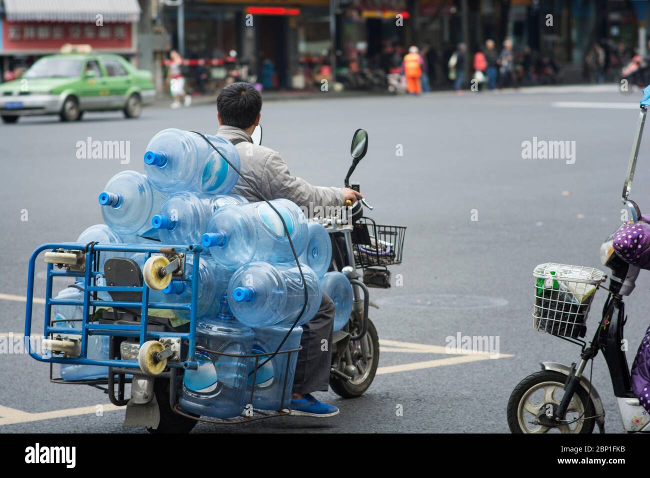 Triciclo electrónico que entrega agua mineral en contenedores de plástico,  en las calles de Chengdu, Sichuan, China Fotografía de stock - Alamy