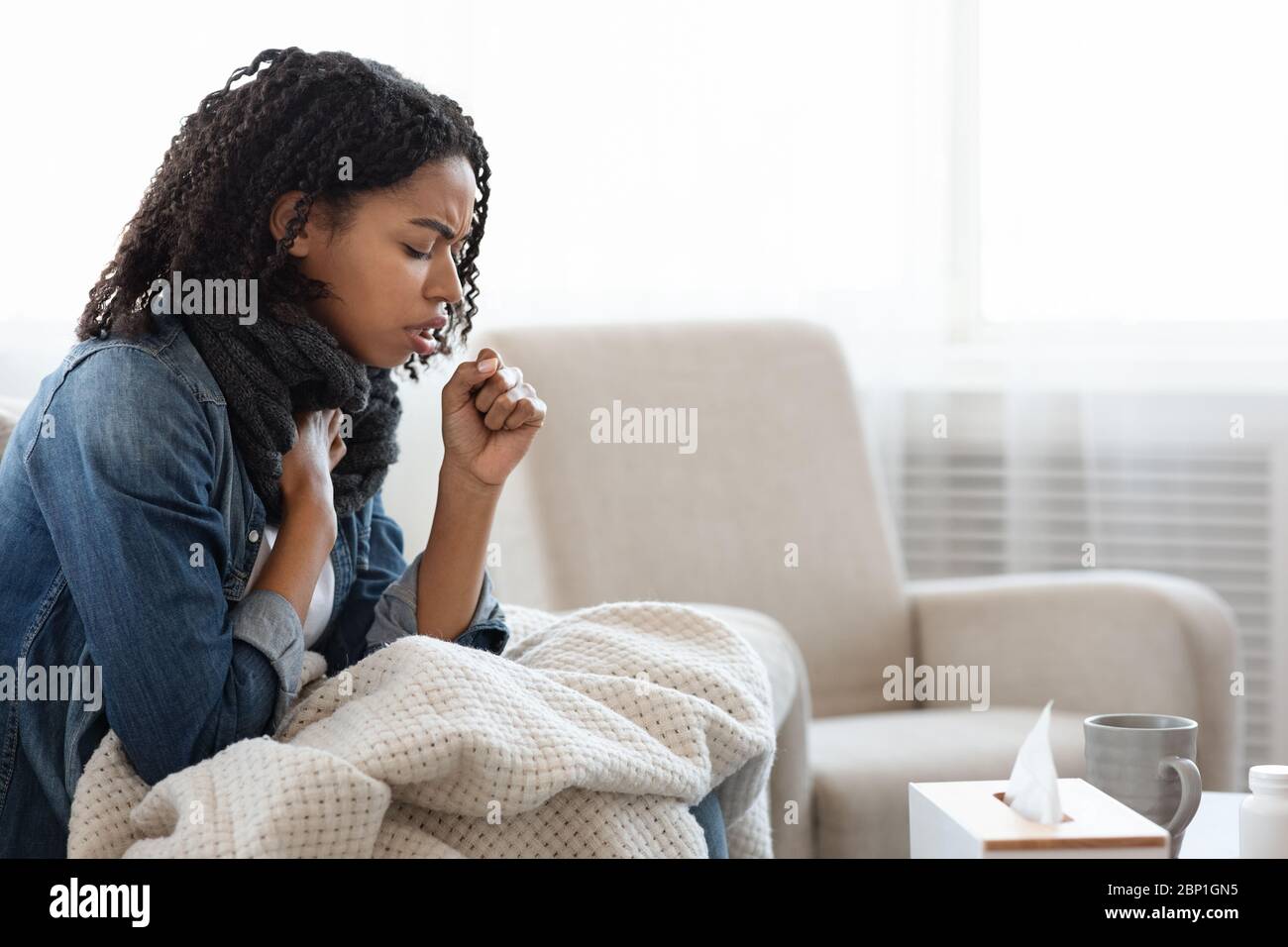Riesgo de coronavirus. Mujer negra enferma tosiendo fuerte en casa Foto de stock