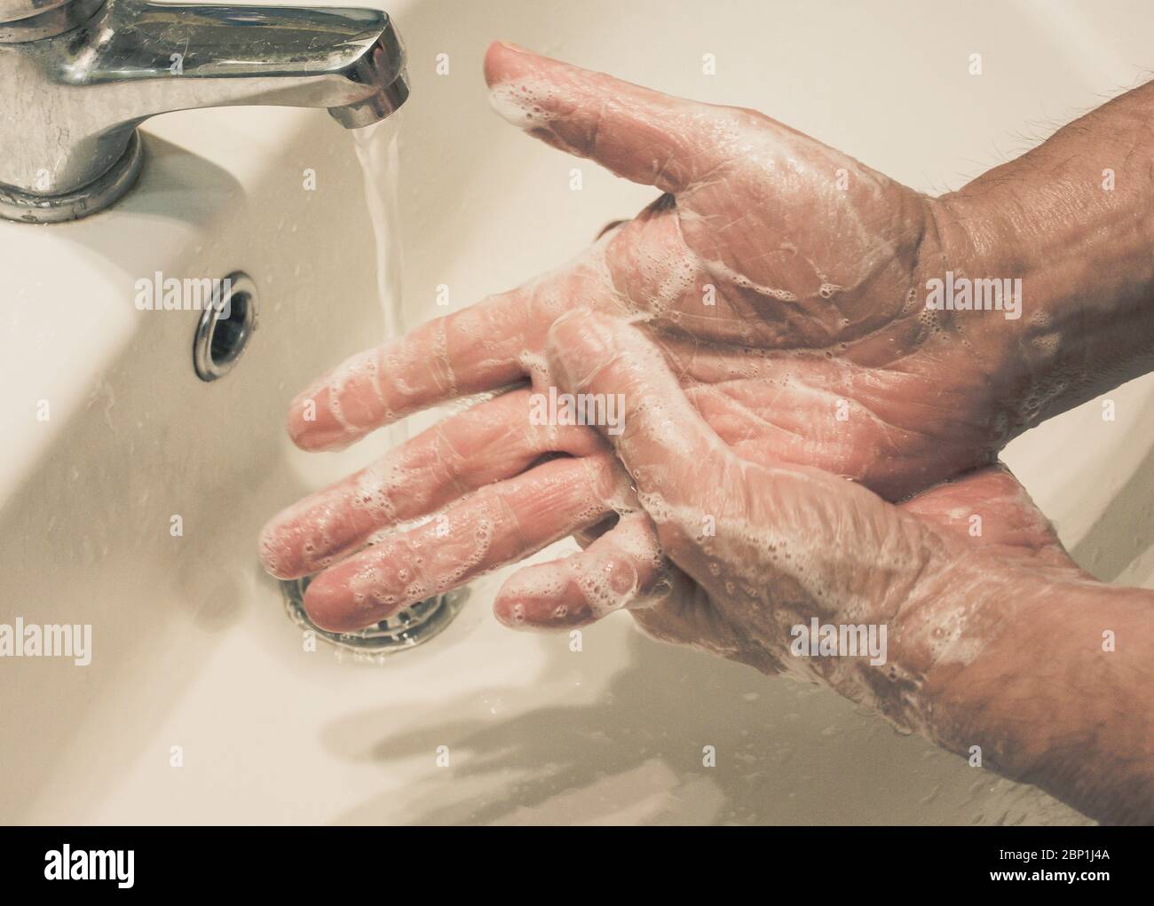 el hombre maduro se lava las manos con agua y jabón fluido. Protección contra infecciones. Lávese las manos contra el virus Foto de stock