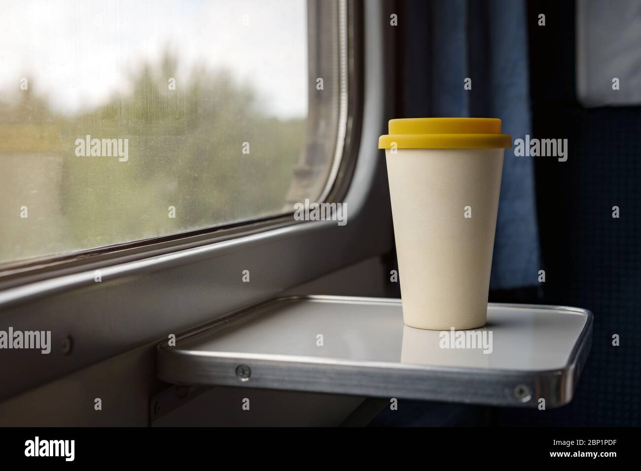 Una taza de café de bambú con una tapa de silicona amarilla Foto de stock