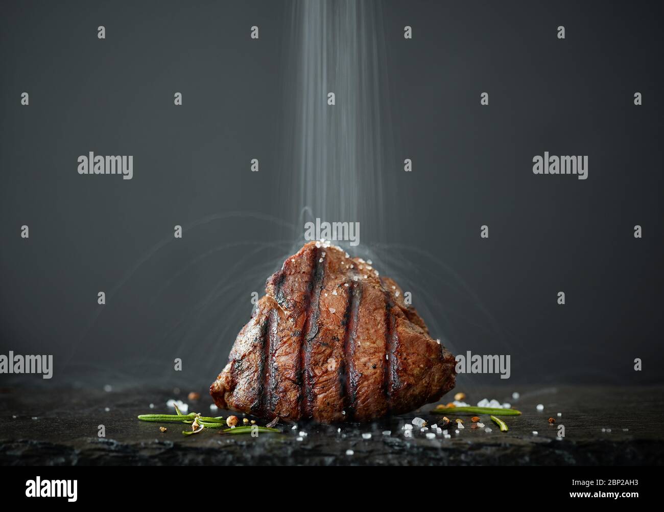 la sal se vierte en un bistec recién asado, tomado con una exposición larga Foto de stock