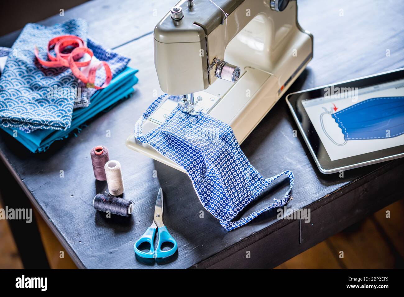 Fabricación de una máscara protectora con una máquina de coser con un tutorial durante la pandemia de Covid 19. Foto de stock