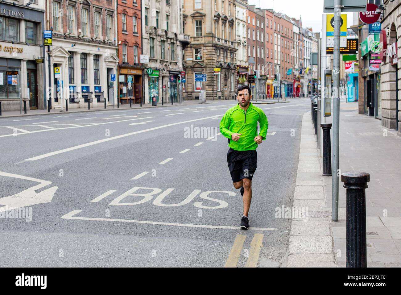 Hombre jogging en la calle desierta Dame en el centro de la ciudad de Dublín. Reducción del tráfico debido a las restricciones de la pandemia del Coronavirus. Mayo de 2020, Dublín, Irlanda Foto de stock