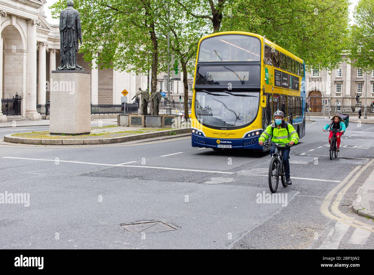 Ciclista con máscara protectora y autobús de Dublín que pasa por College Green en el centro de la ciudad de Dublín. Restricciones pandémicas Covid-19. Foto de stock