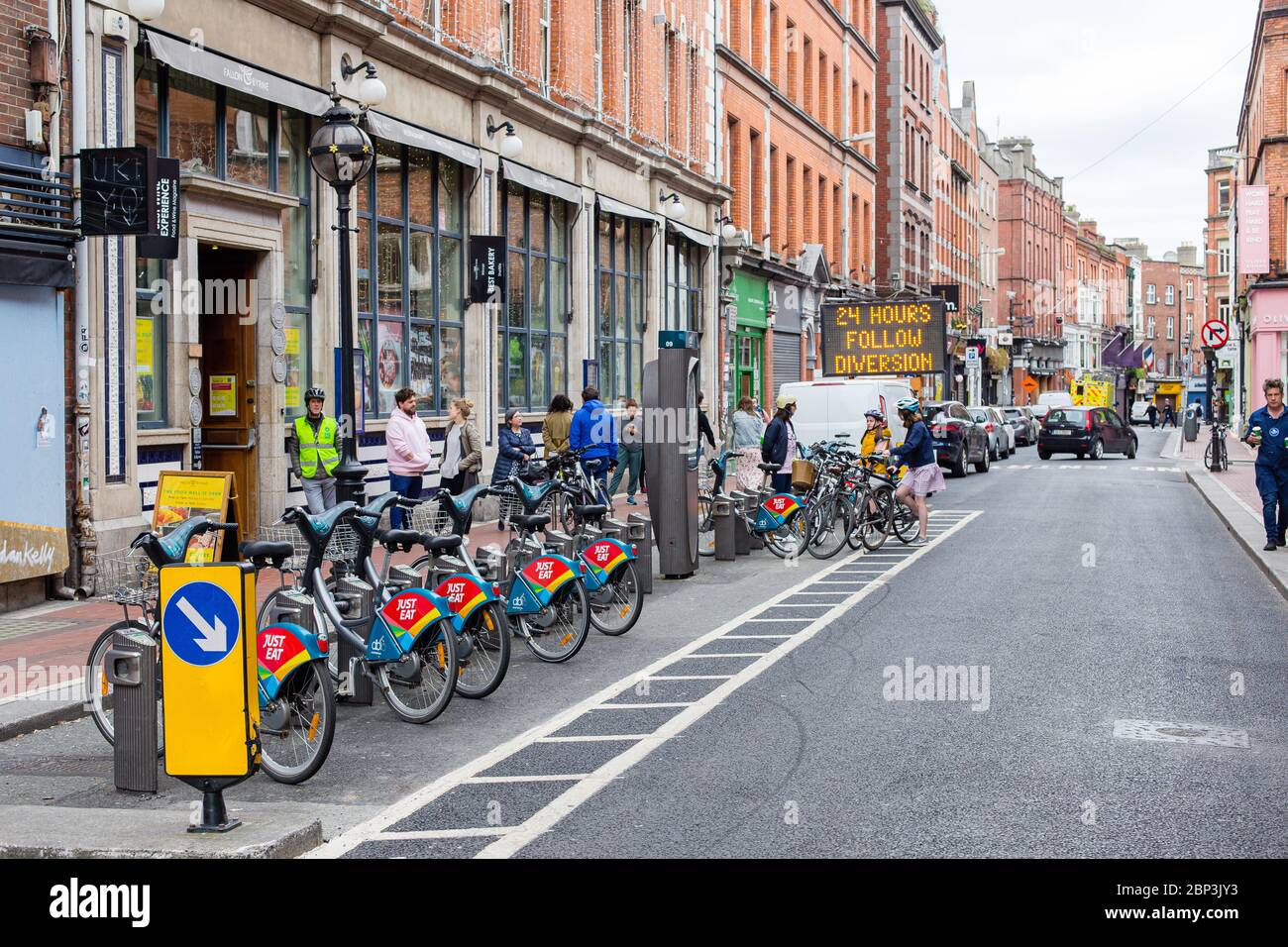 Los compradores que hacen cola en la tienda de comestibles al lado de la estación de bicicletas en Wicklow Street en el centro de la ciudad de Dublín durante las restricciones pandémicas Covid-19 Foto de stock