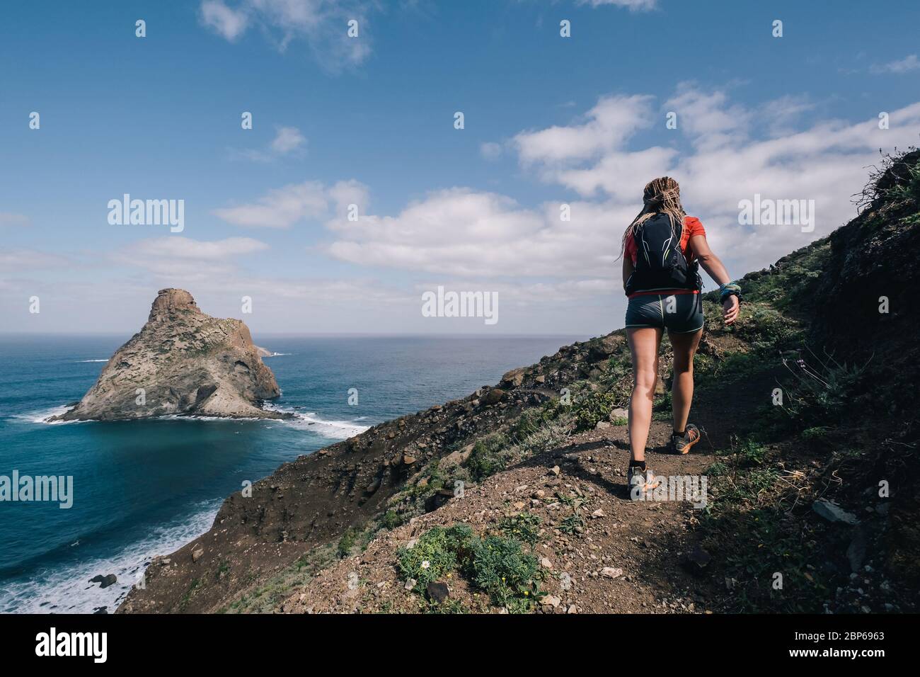 Mujer corre a través del campo en un camino en el camino de montaña en la isla de Canarias. Vistas al océano Foto de stock