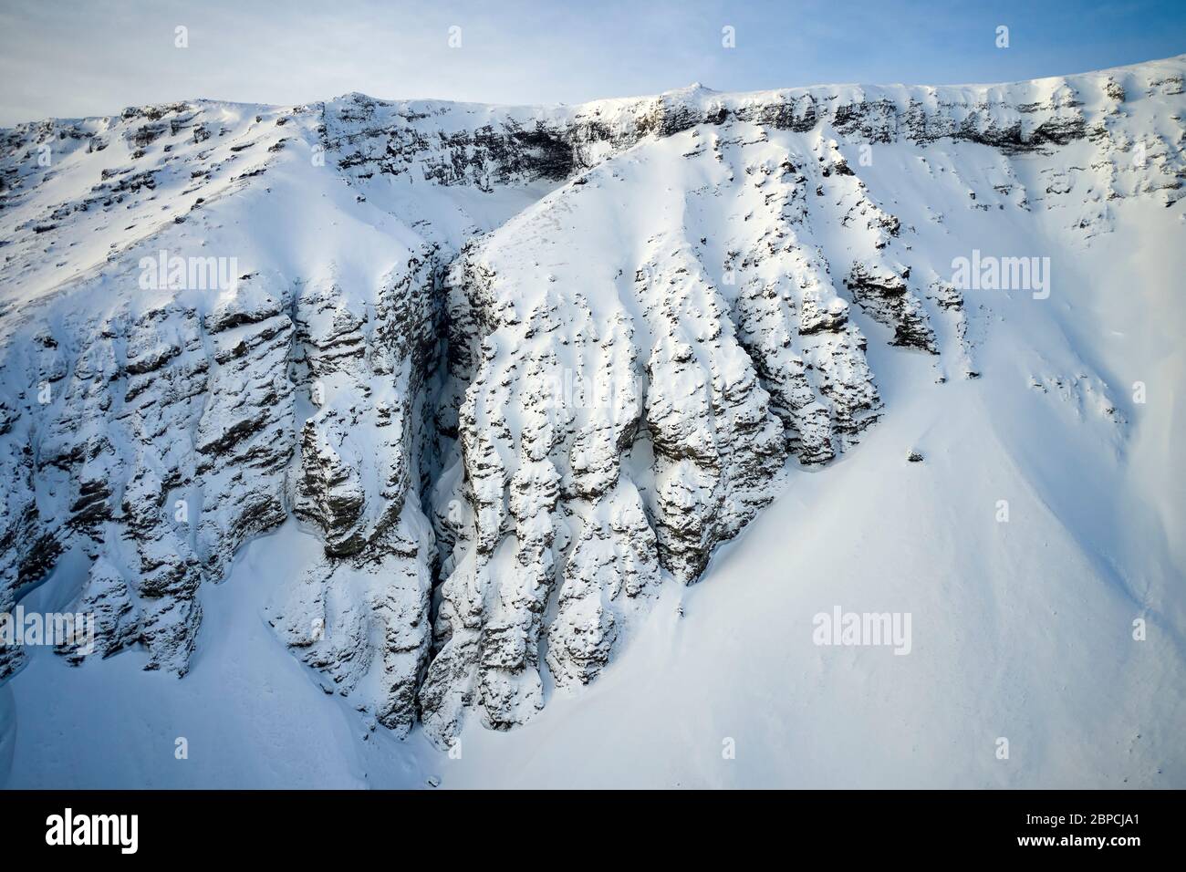 Vista aérea de la cordillera con pendientes escarpadas cubiertas de nieve en Islandia Foto de stock