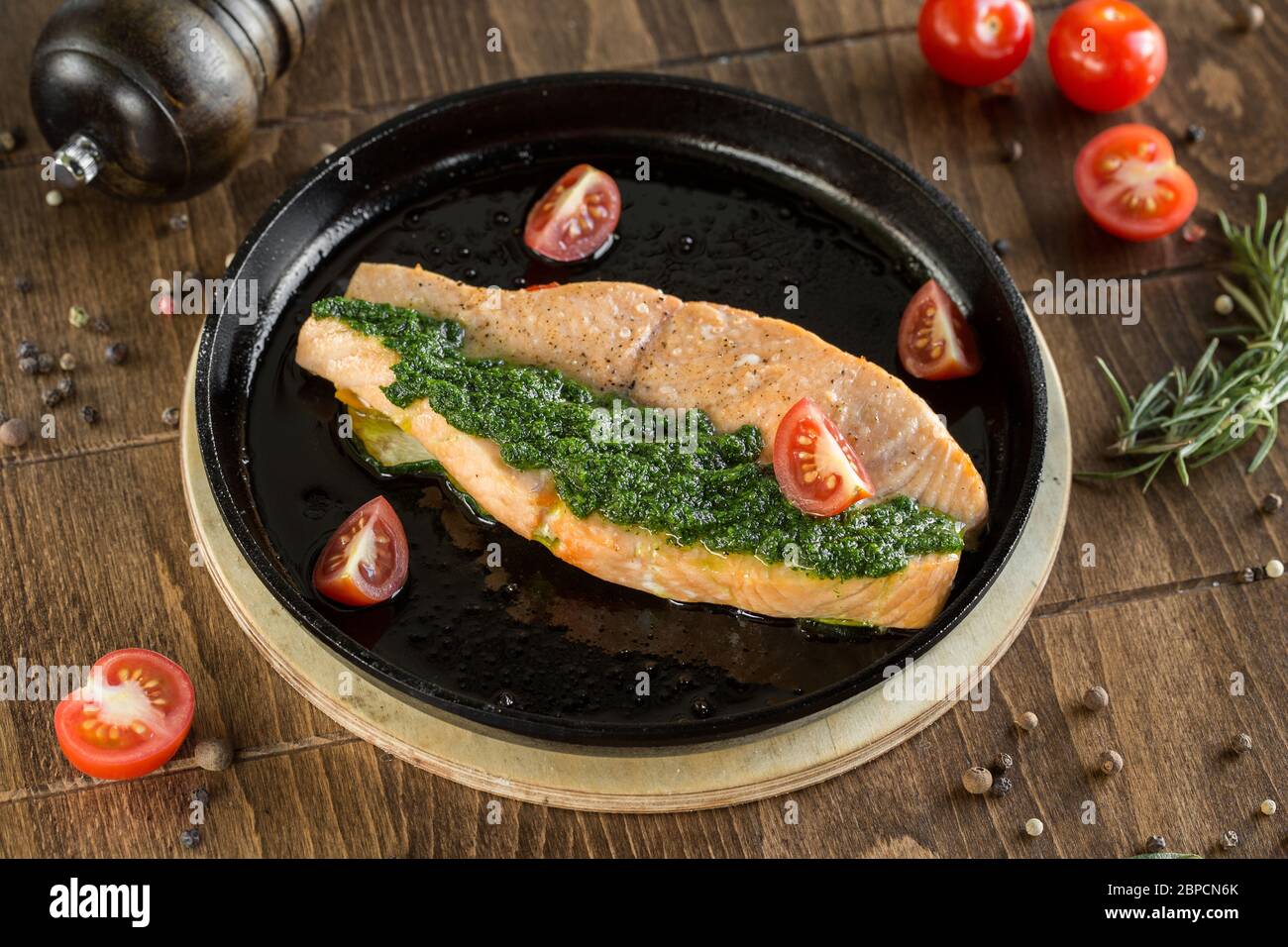 Filete de pescado rojo a la parrilla. Servido en una sartén con tomates cherry y pesto. Foto de stock