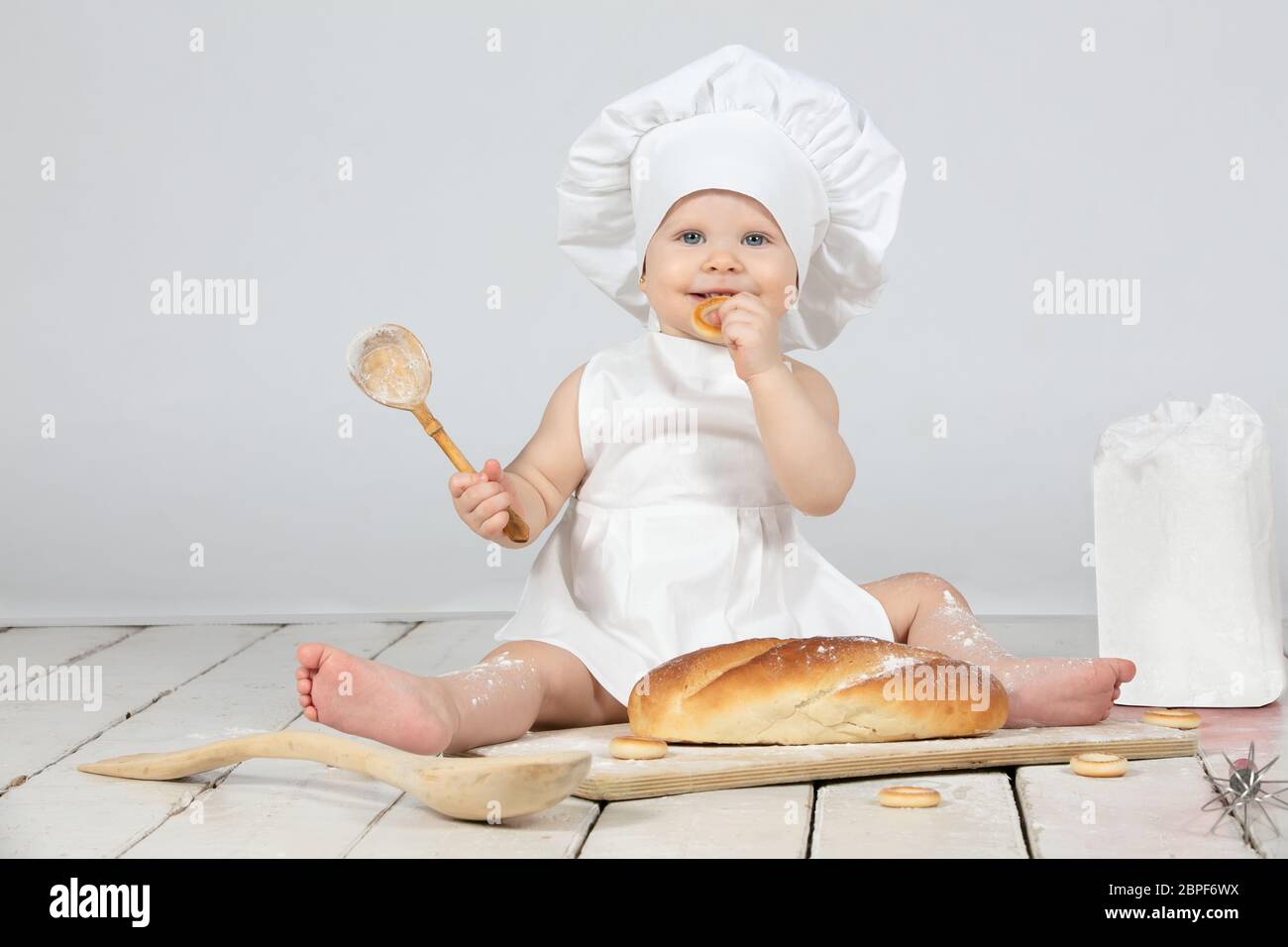 Nino Cocinero Hermosa Nina En La Ropa De Cocina Con Un Largo Pan Y Una Cuchara De Madera En La Harina El Nino Tiene Un Ano De Edad Bebe Divertido Pequeno Chef