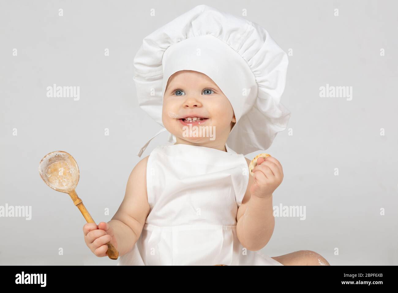 Nino Cocinero Hermosa Nina En La Ropa De Cocina Con Una Cuchara Grande El Nino Tiene Un Ano De Edad El Bebe Divertido Se Rie Pequeno Chef El Concepto De Coo Fotografia