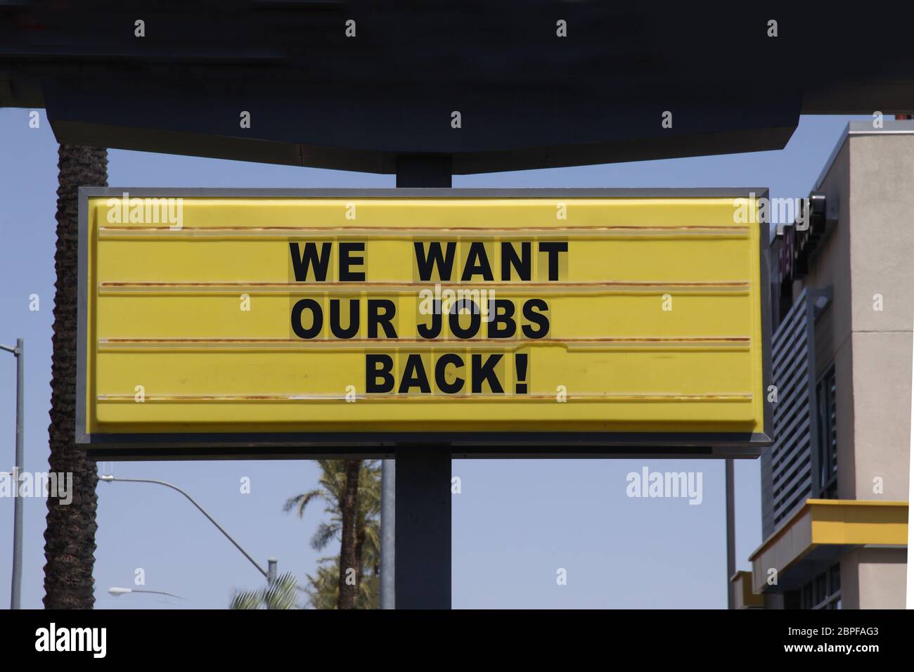 Billboard diciendo que queremos nuestros trabajos de vuelta con palmeras y fondo azul cielo. Protestas contra el cierre de la cárcel. Foto de stock
