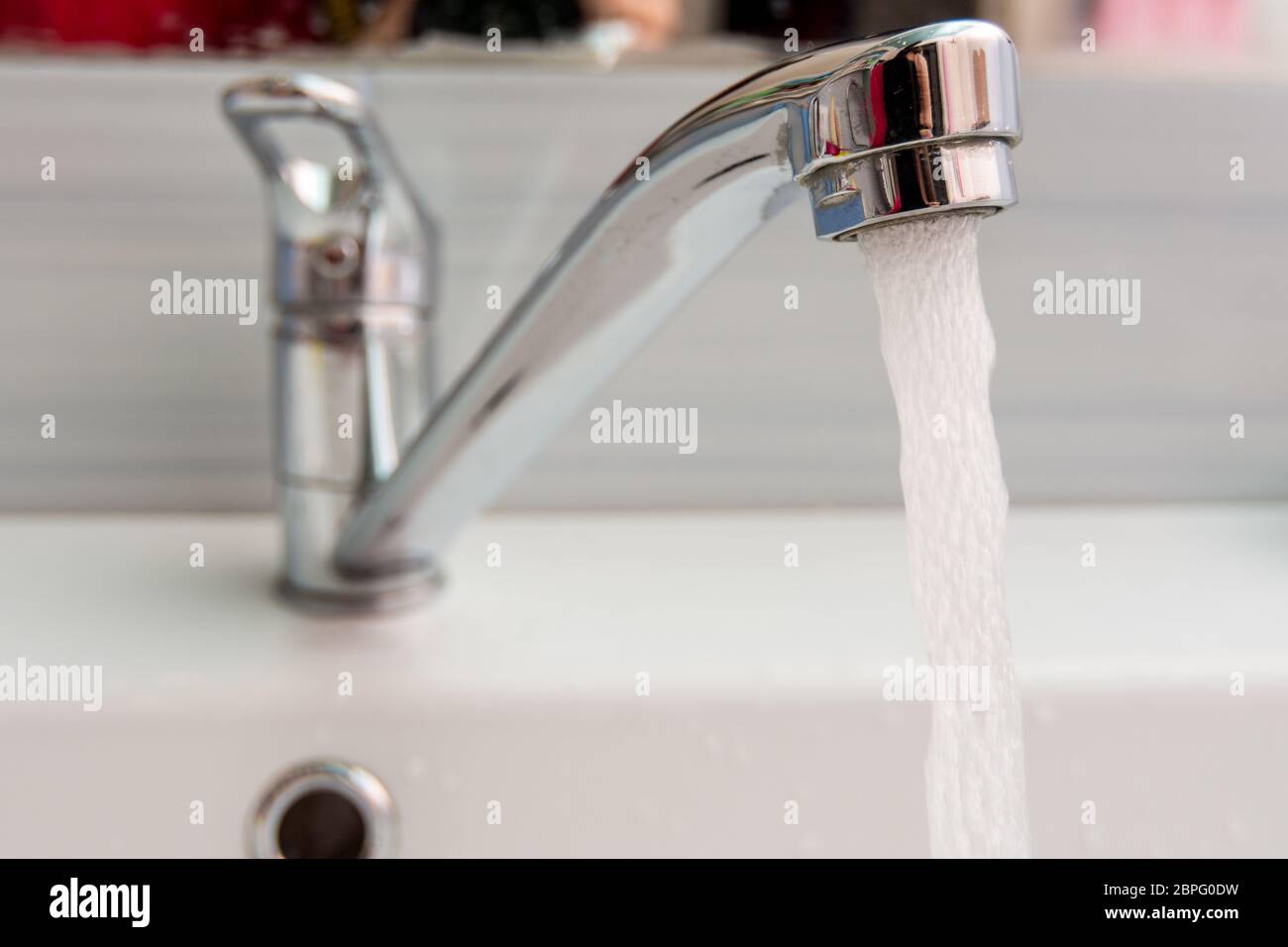 El agua fluye más presión desde el mezclador en el baño Foto de stock