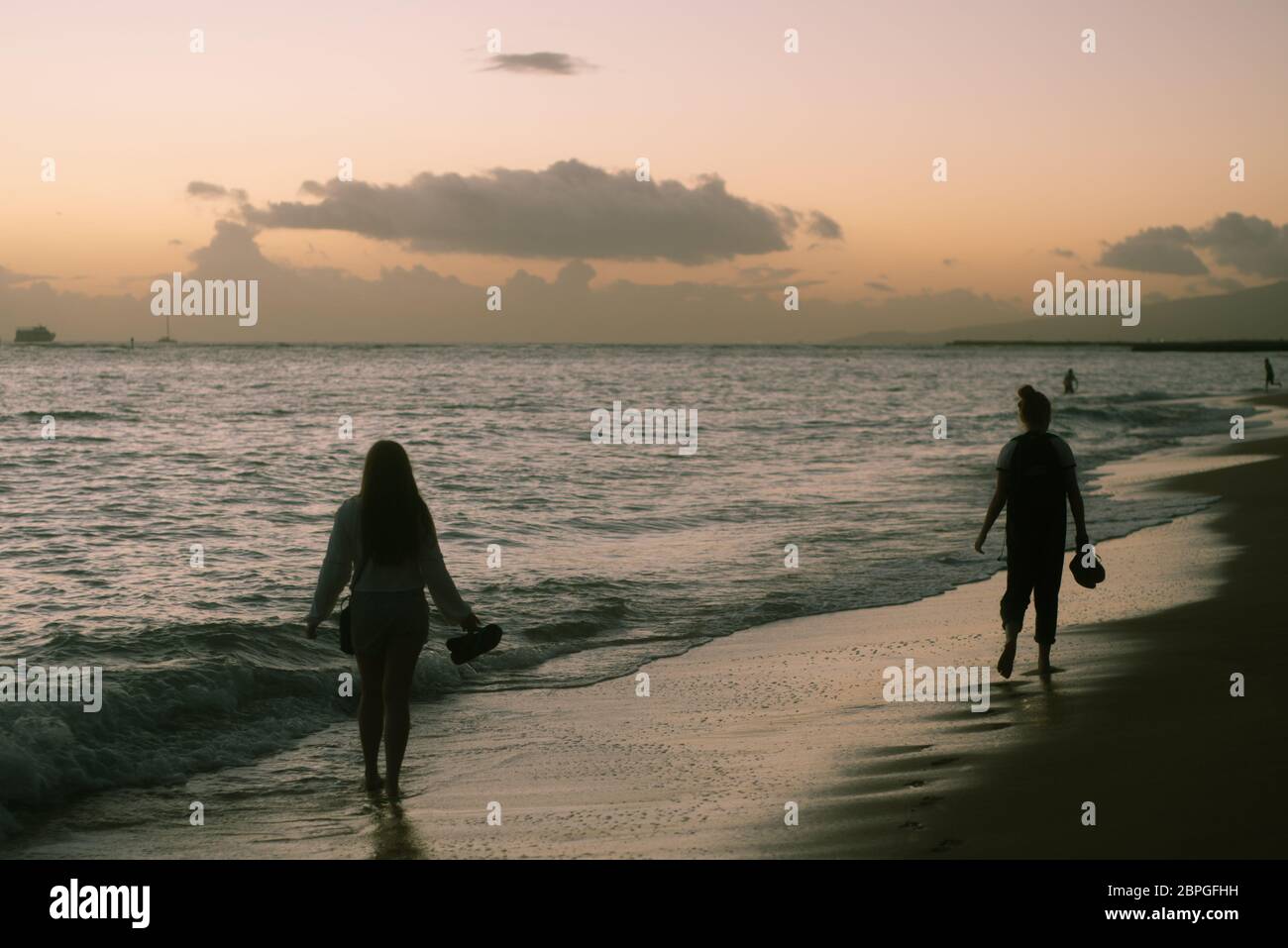 Hermanas caminan a lo largo de la costa en la playa en la isla de Oahu en Dusk Foto de stock
