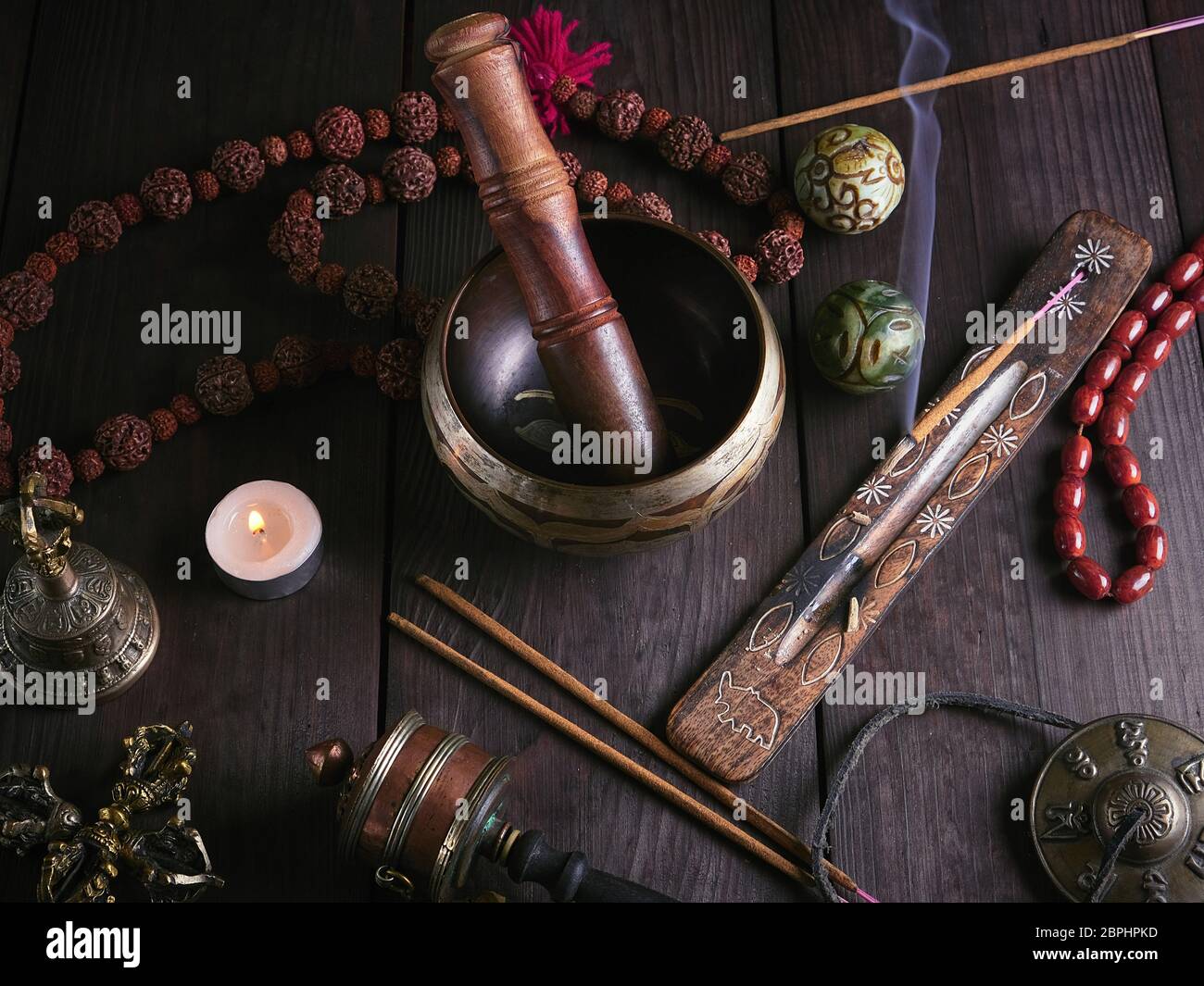 Canto de cobre bowl, el rosario, la oración de tambor, bolas de piedra y  otros objetos religiosos tibetanos para la meditación y la medicina  alternativa sobre una plancha de madera ba Fotografía