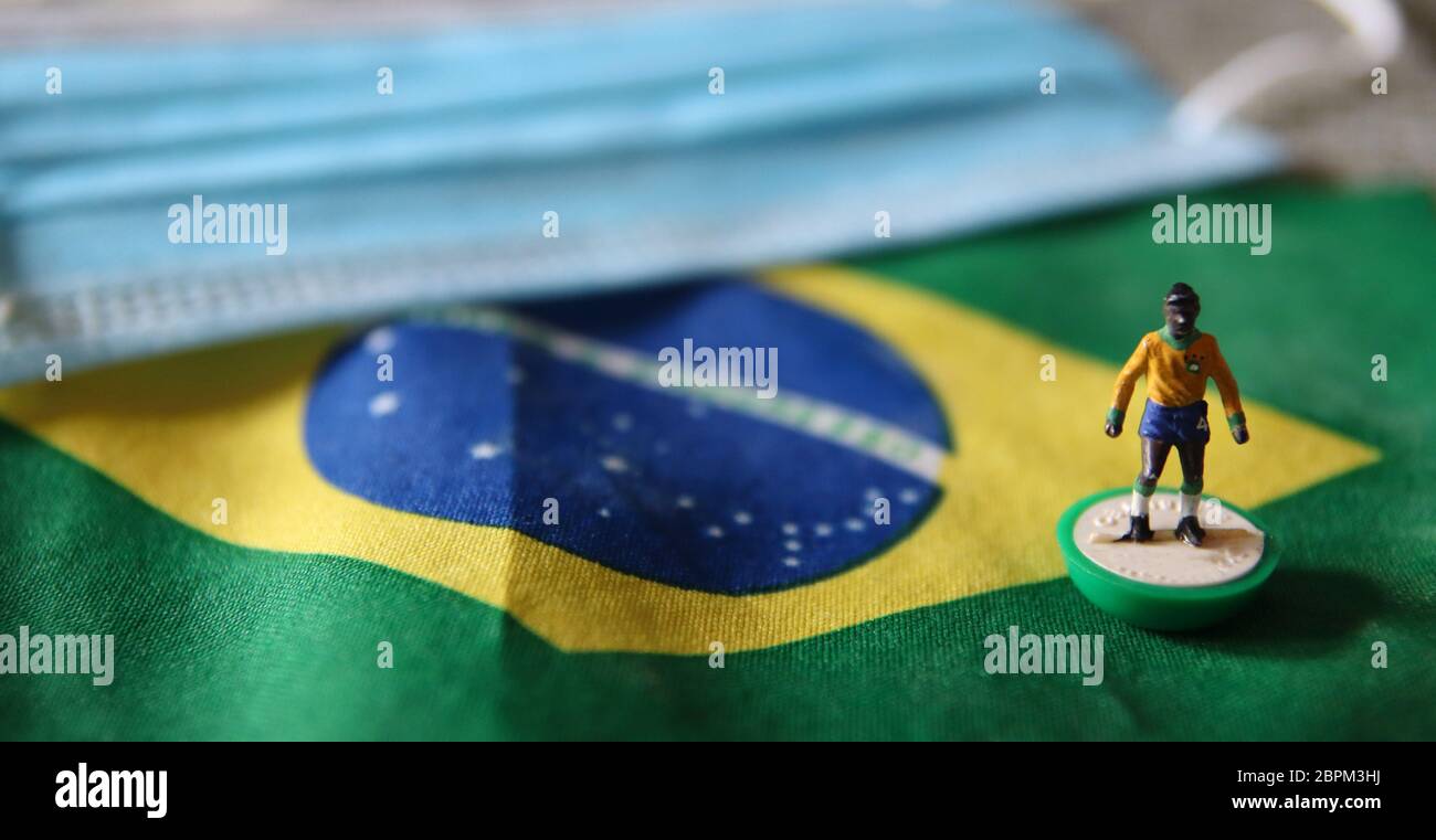 Bandera de Brasil y máscara quirúrgica con un futbolista plástico para la Prevención del Coronavirus - pandemia de Covid19 Foto de stock