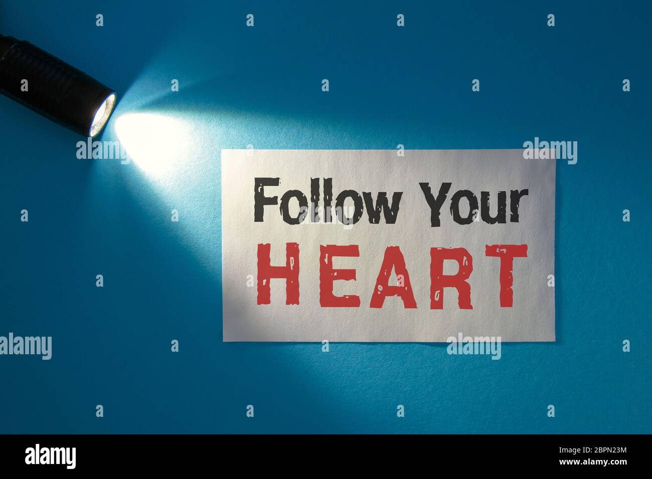 Sigue tu corazón - inscripción en una tarjeta blanca en el haz de luz Foto de stock