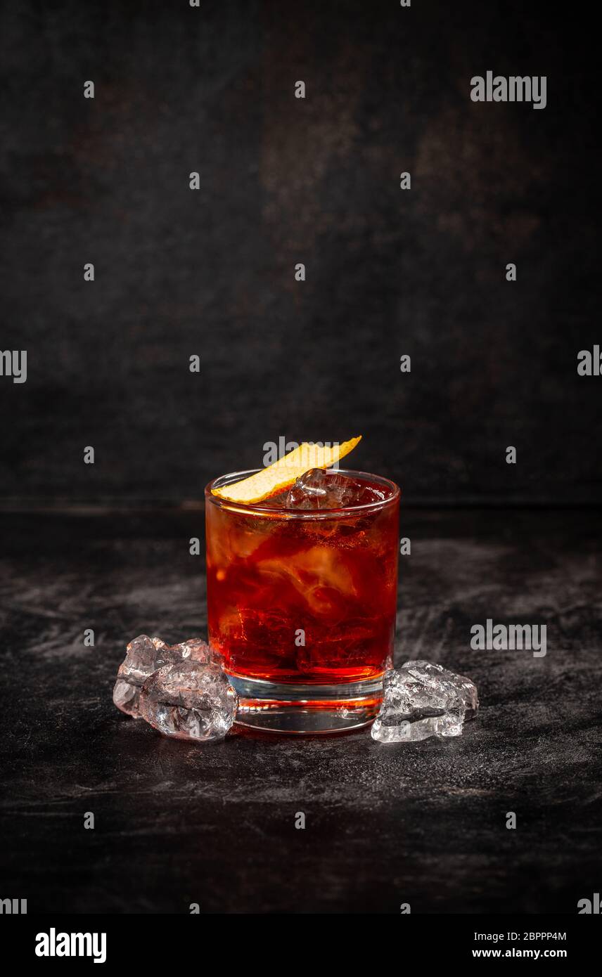 Cóctel Negroni decorado con cáscara de naranja sobre fondo oscuro Foto de stock