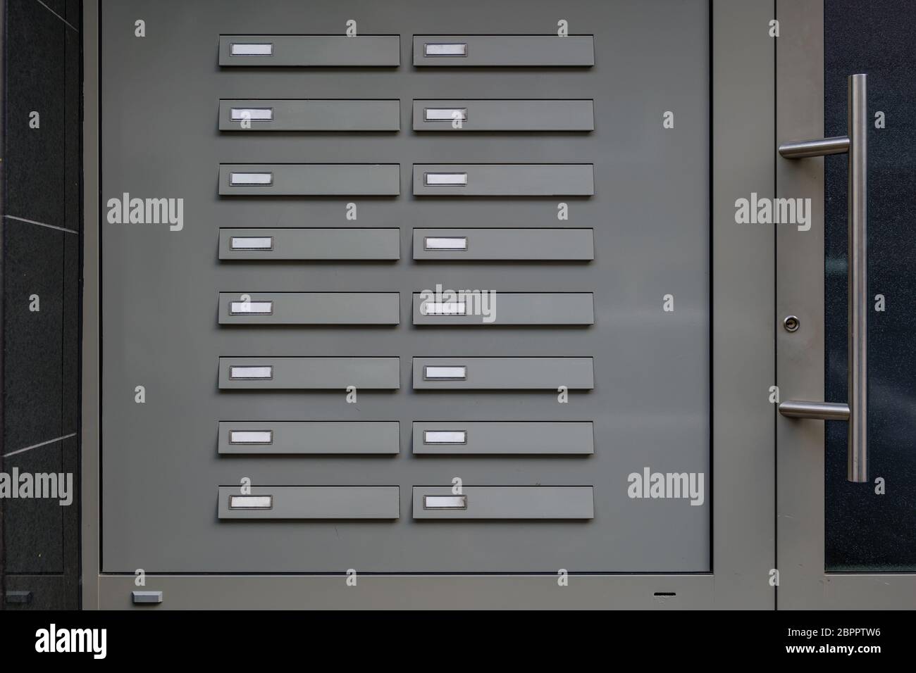 Campanas de puerta de metal con etiquetas de nombre vacías. Timbre de puerta sin nombres junto a la puerta de entrada del apartamento. Foto de stock