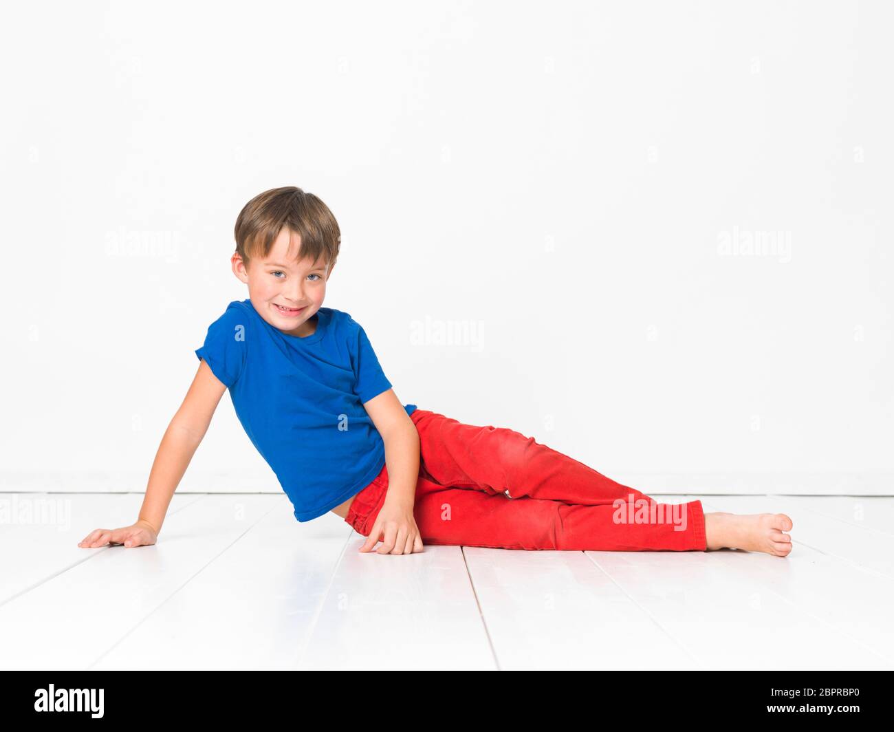 Fraude Catedral Residencia Cool, muchacho de seis años con pantalón rojo y camisa azul sobre blanco  piso Fotografía de stock - Alamy
