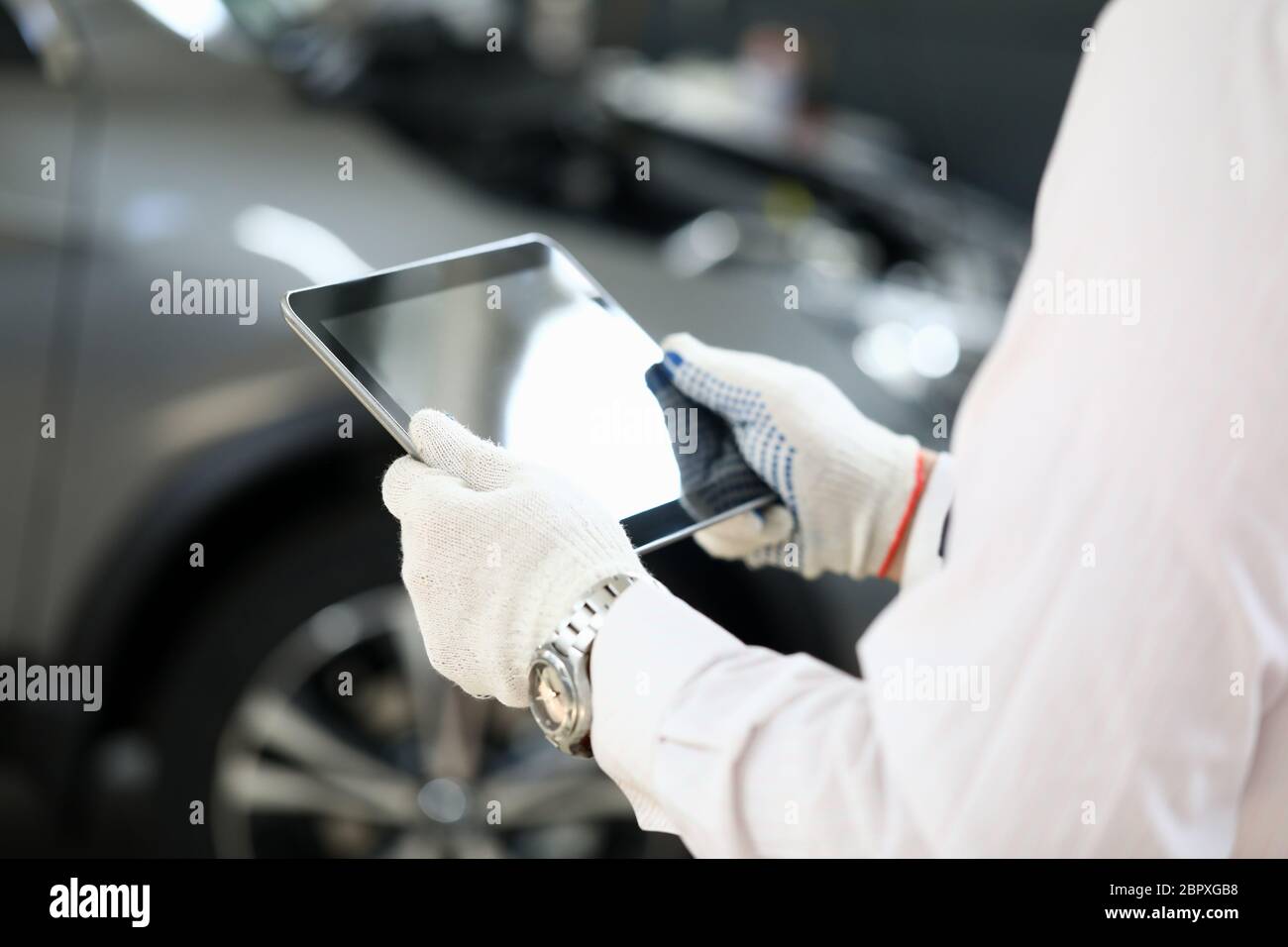 El hombre sostiene la tableta cerca del coche para solucionar problemas Foto de stock