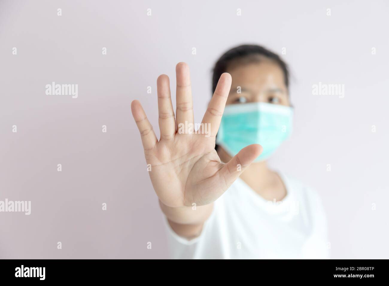 La epidemia de gripe, Coronavirus o COVID-19 y el concepto de enfermedad. Las mujeres usan una máscara médica para la protección y demuestran las manos de la parada gesturing a St Foto de stock