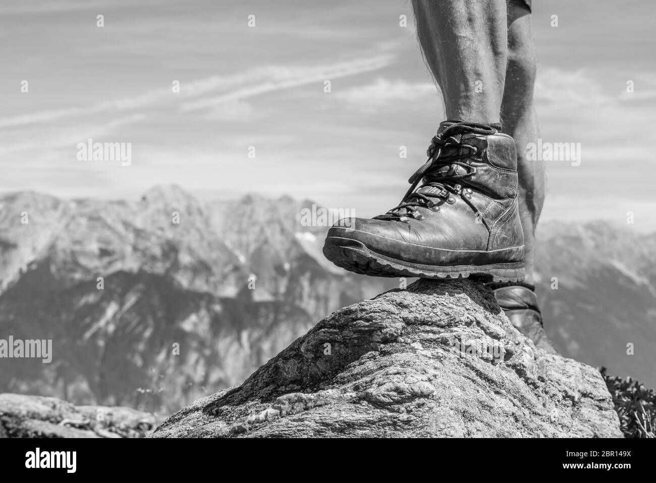 Escoba Unidad desbloquear Calzado de cuero para senderismo de un hombre pisando una pequeña roca en  el valle de Ziller, Austria. Alcanzar el pico con una hermosa cordillera  alpina en el b Fotografía de stock -