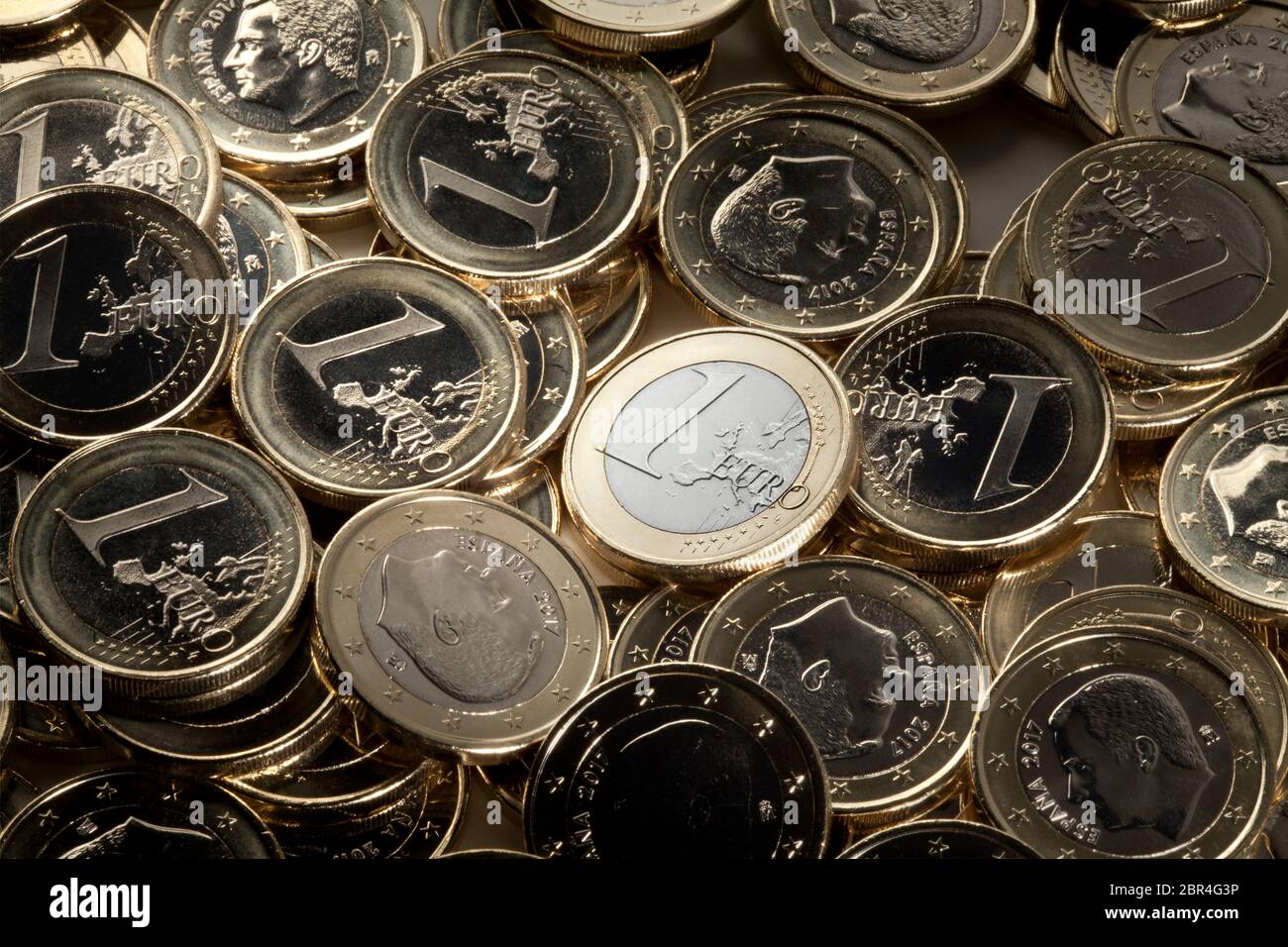 Una moneda de euro prominente entre muchas piezas de euro. Foto de stock