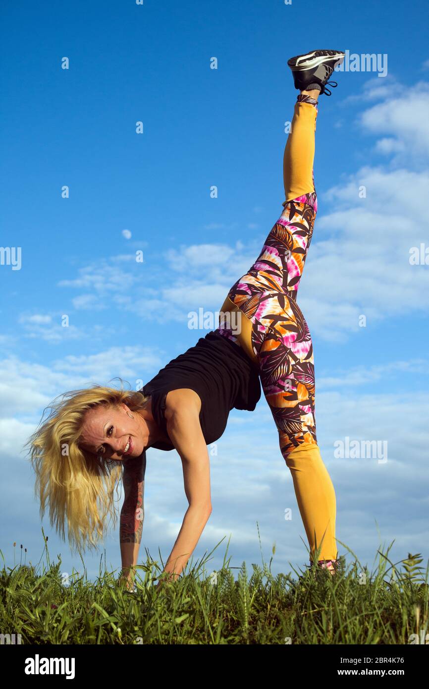 La mujer sonriente y atractiva de mediana edad se está estirando y haciendo ejercicios al aire libre en la naturaleza. Foto de stock