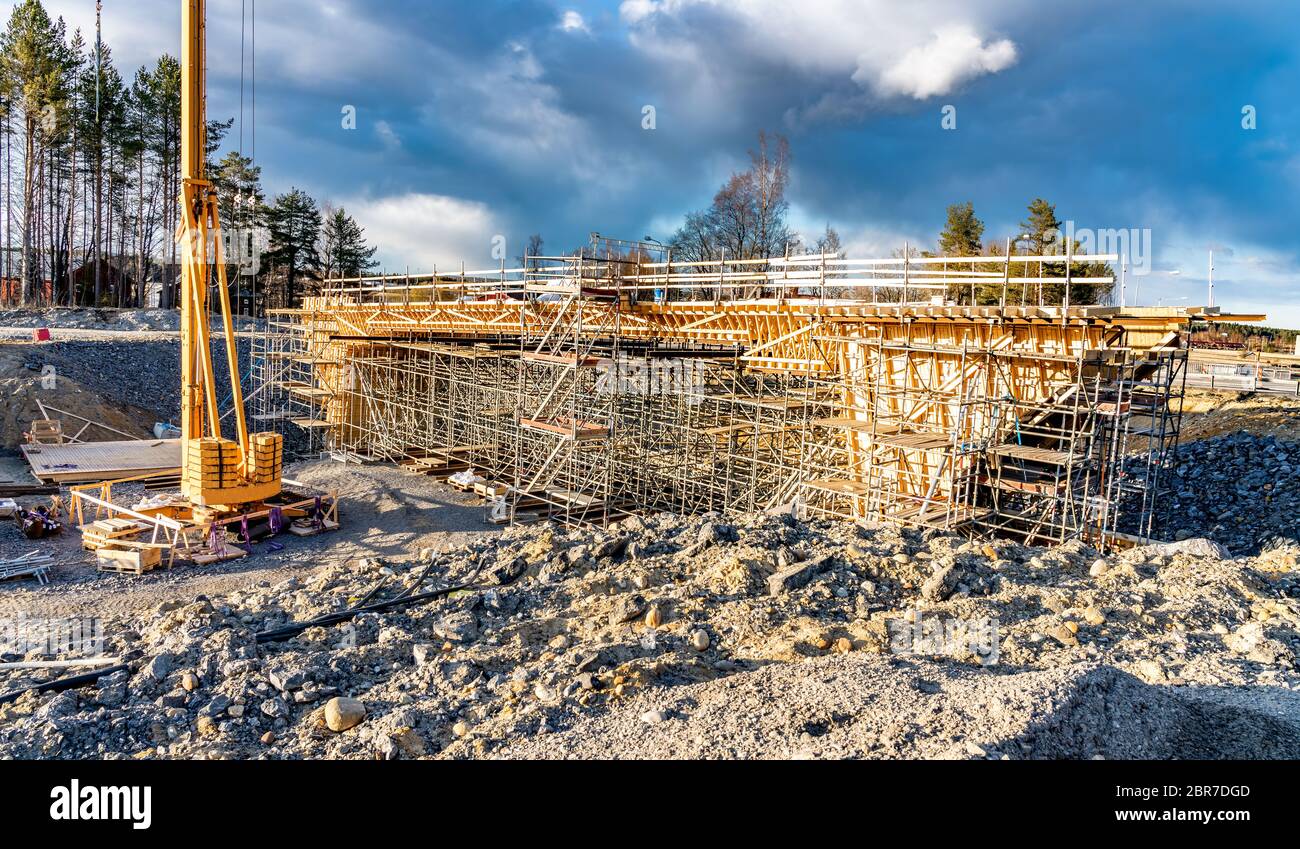 Foto de cerca del nuevo puente con construcción de madera para llenarlo aún más de hormigón. Torre de la grúa amarilla, nubes azules, cielo profundo Foto de stock