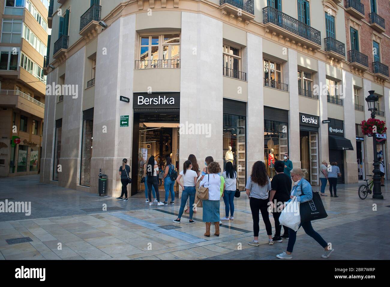 La gente espera en cola fuera de la tienda de ropa 'Bershka' en la calle  Marques de Larios durante un cierre parcial a nivel nacional. España está  pasando por un plan de