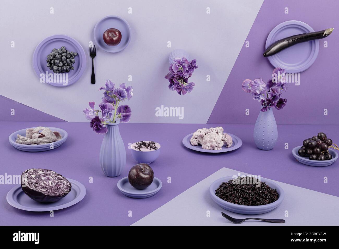 Mesa puesta en violeta, perspectiva, surrealista, berenjena, col roja, arroz, yogur, uvas, manzana, flores, coliflor, vida, fotografía de alimentos Foto de stock