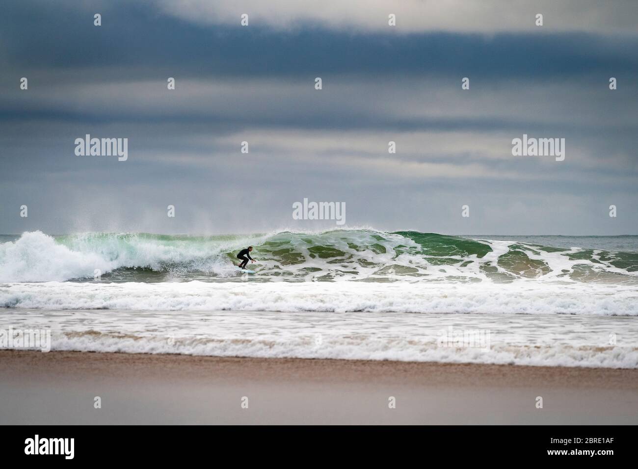 Carcavelos, Portugal - 9 de enero de 2020: Un surfista montando una ola en la playa de Carcavelos en una mañana de invierno. Foto de stock