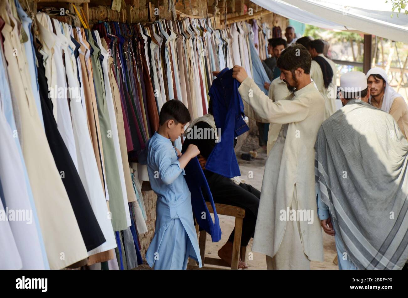 Peshawar, Pakistán. 21 de mayo de 2020. Un hombre vende ropa usada antes  que Eid al-Fitr en Peshawar. Eid al-Fitr es una fiesta islámica que Marca  el final del Ramadán, y se