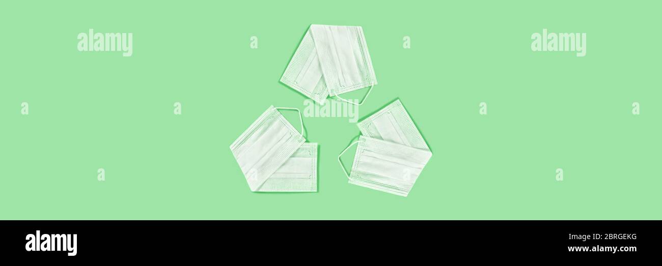 El símbolo universal de reciclaje hecho de las máscaras médicas sobre fondo verde. Foto de stock