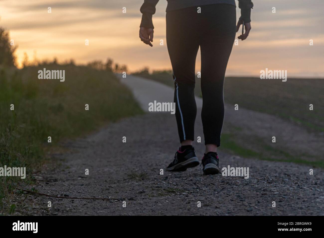 La mitad inferior de una dama tomando un descanso caminando durante su jogging de noche Foto de stock