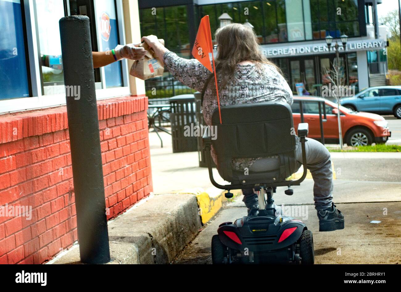 Mujer en silla de ruedas motorizada recibiendo alimentos en la ventana de conducción Dairy Queen manteniendo la distancia social CORONA-19 pandemia. St Paul Minnesota Minnesota Minnesota, Minnesota, EE.UU Foto de stock