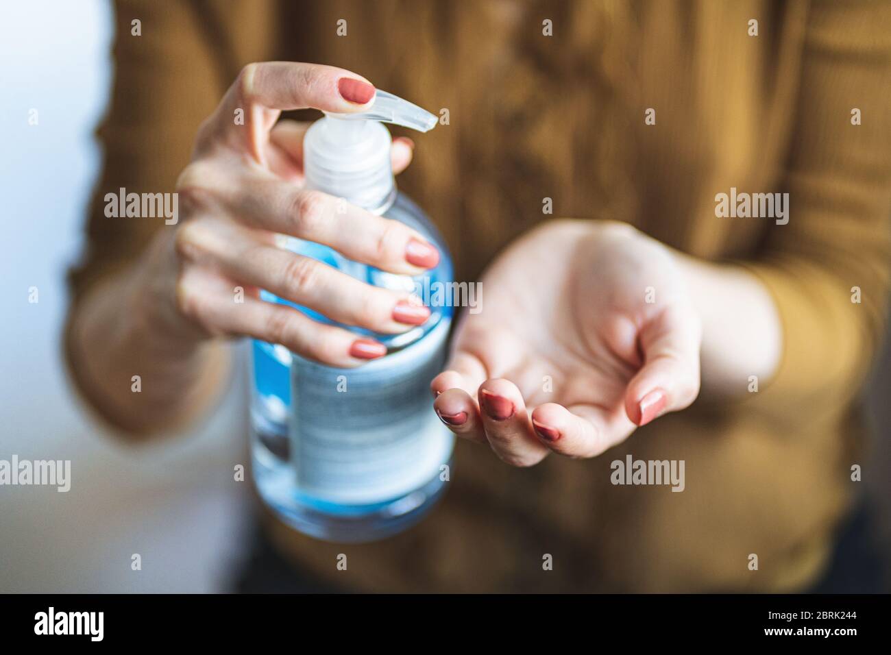 Cierre las manos de las mujeres usando el dispensador de gel desinfectante para manos durante el brote epidémico de coronavirus. Lavarse las manos con desinfectante para manos para evitar el contacto Foto de stock