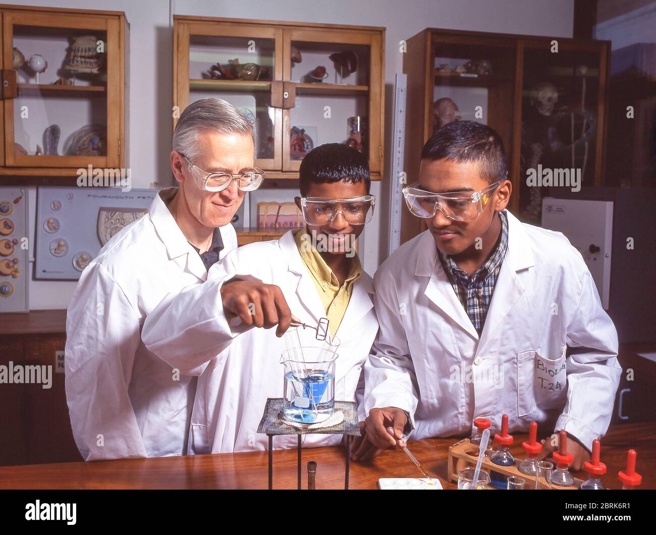Estudiantes asiáticos que hacen experimentos químicos en clase de ciencias, Surrey, Inglaterra, Reino Unido Foto de stock