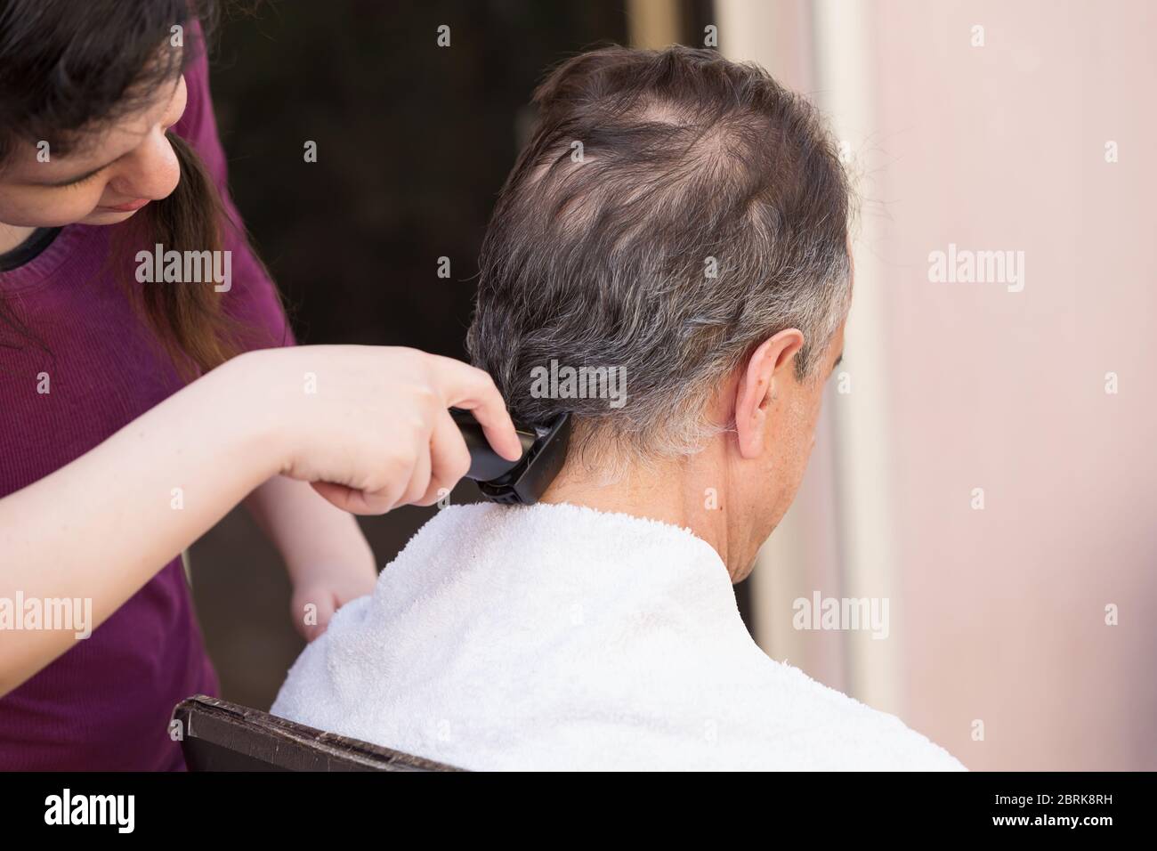 Miembro de la familia cortando el pelo de los hombres en casa Foto de stock