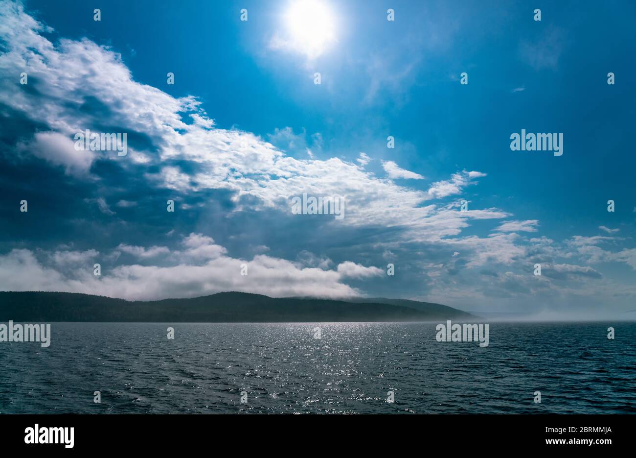 La niebla marina que se depositan sobre el mar desaparece bajo el fuerte sol de la mañana, casi ningún viento, cielos azules Foto de stock