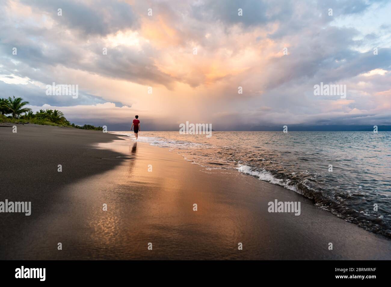 Adolescentes caminando en la playa con reflexión en Costa Rica Foto de stock