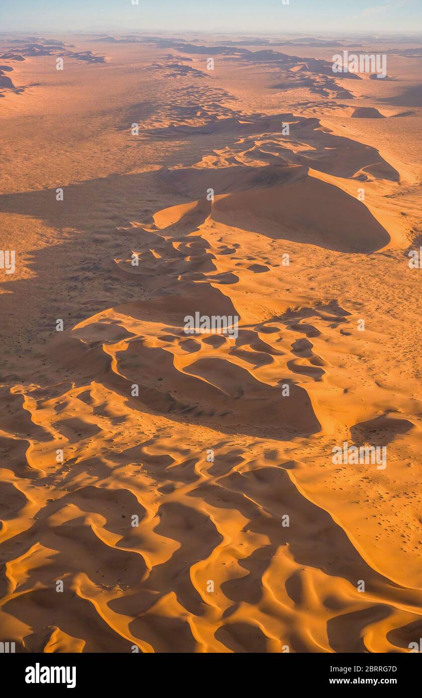 Imagen vertical de las hermosas y dramáticas dunas de arena del desierto de Namib en Sossussvlei, Namibia, disparadas desde un helicóptero al atardecer. Foto de stock