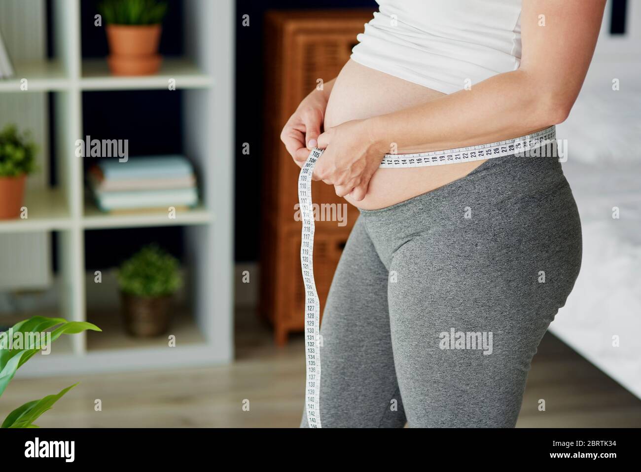 Mujer embarazada que comprueba la medida del abdomen Foto de stock