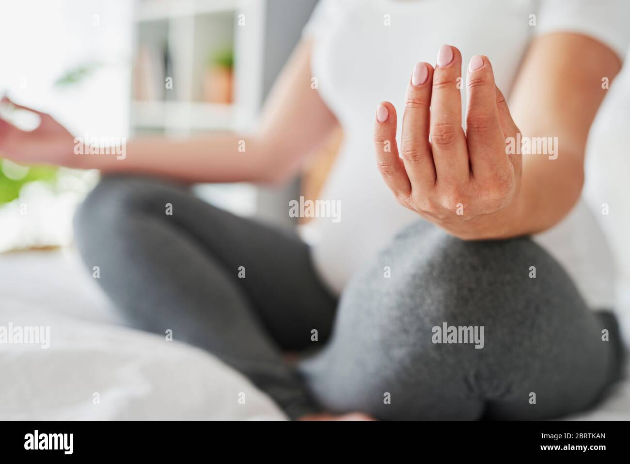 Mujer embarazada meditando mientras estaba sentada en la cama Foto de stock