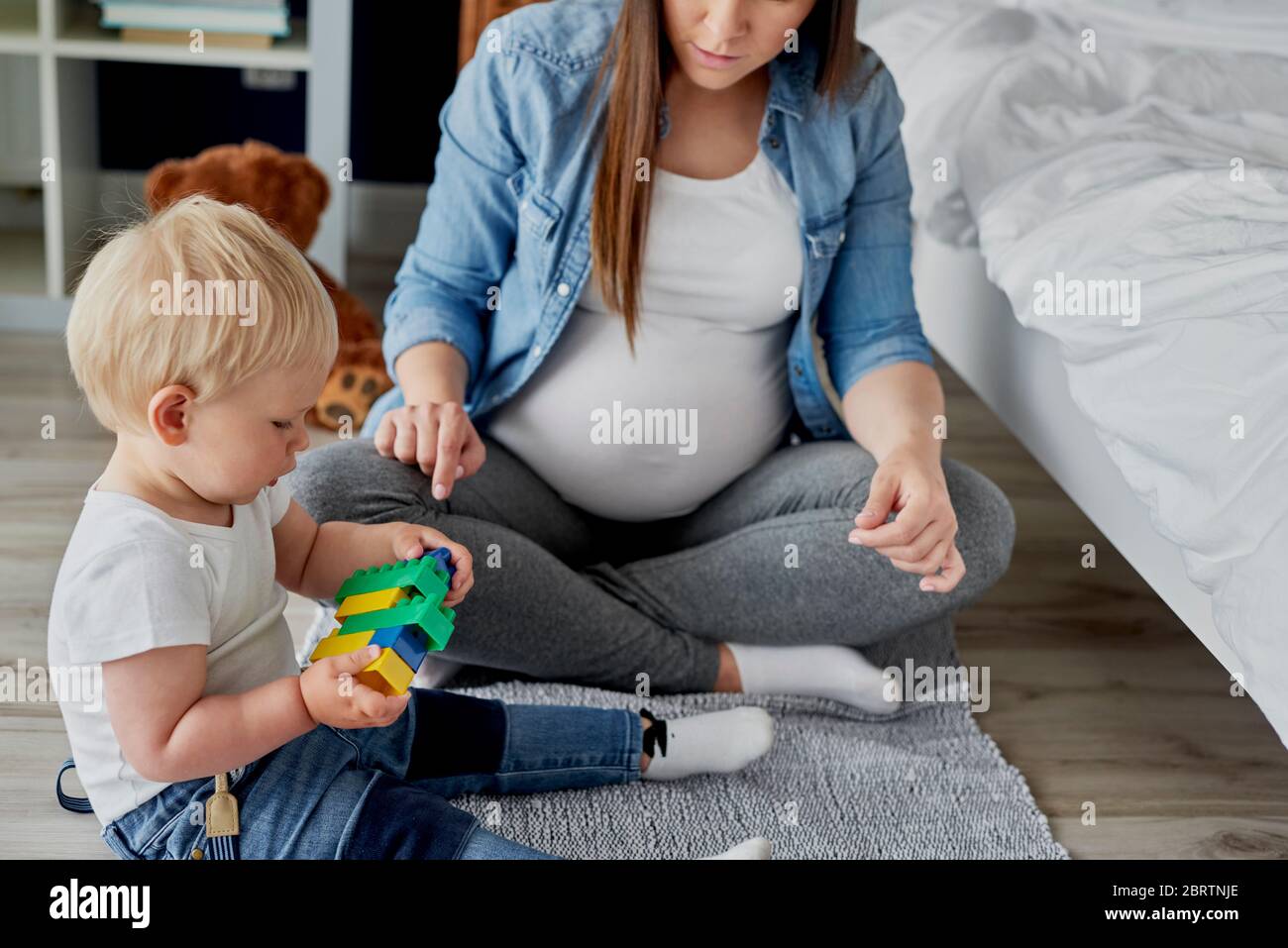 Madre embarazada jugando bloques de juguetes con su hijo Foto de stock