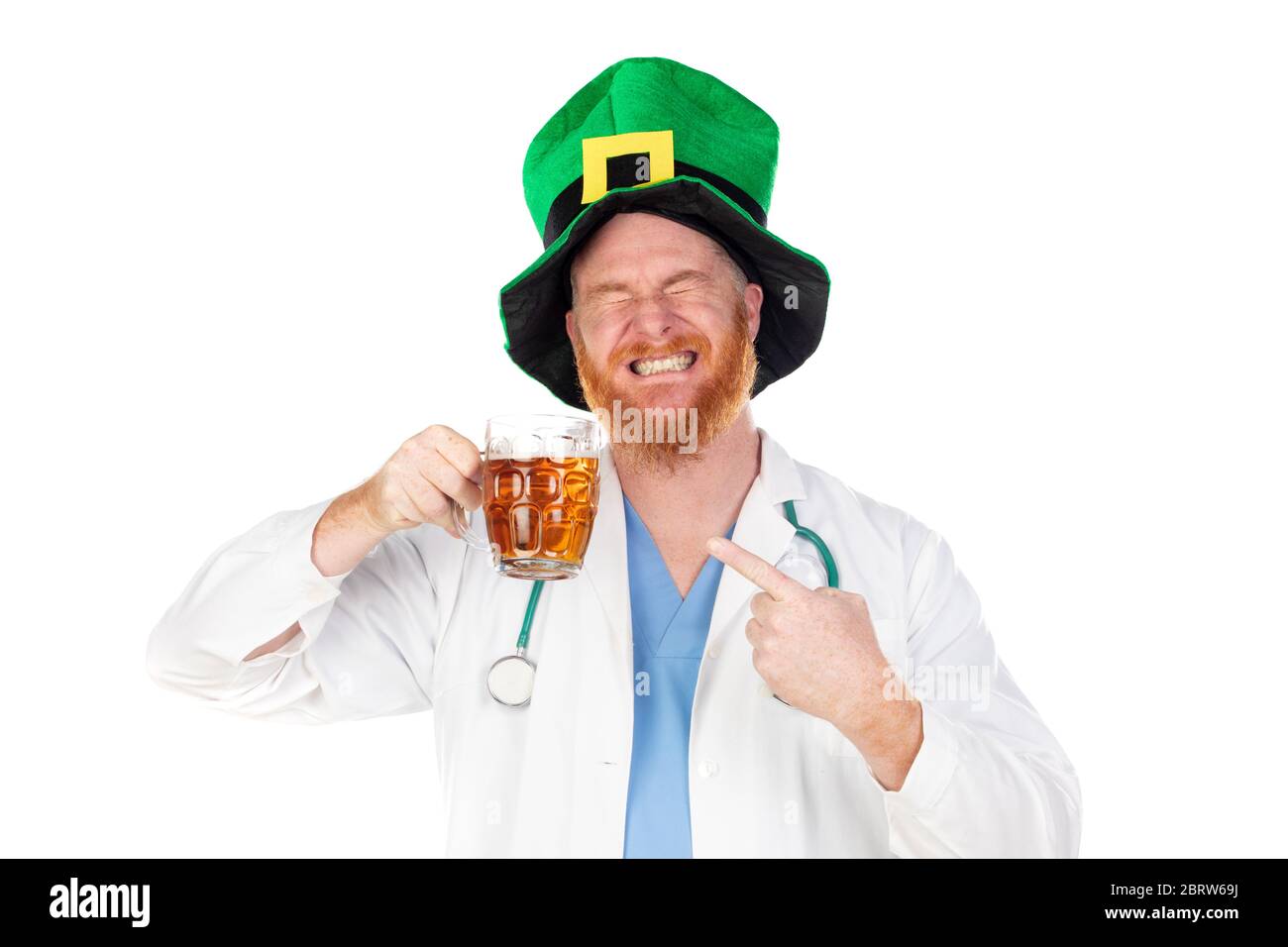 Médico de la cabeza roja con sombrero verde bebiendo una cerveza aislada sobre un fondo blanco Foto de stock