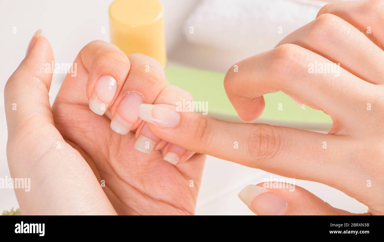 Manicura. Una mujer aplica aceite de cutícula a sus uñas. Cuidado de las  uñas. Uñas largas naturales. Sin pintar. Hidratante. Manicura francesa.  Cuidado de la piel, SPA, belleza sa Fotografía de stock -