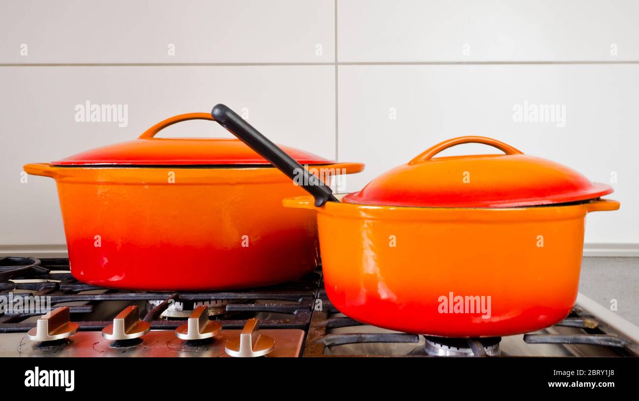 dos ollas de color naranja brillante de hierro fundido con esmalte en una  antigua estufa de gas Fotografía de stock - Alamy