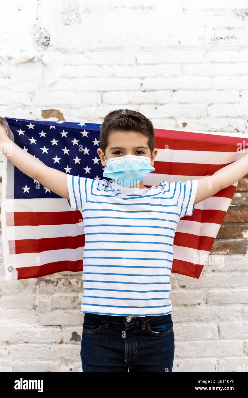 Niño pequeño con bandera americana y máscara Foto de stock