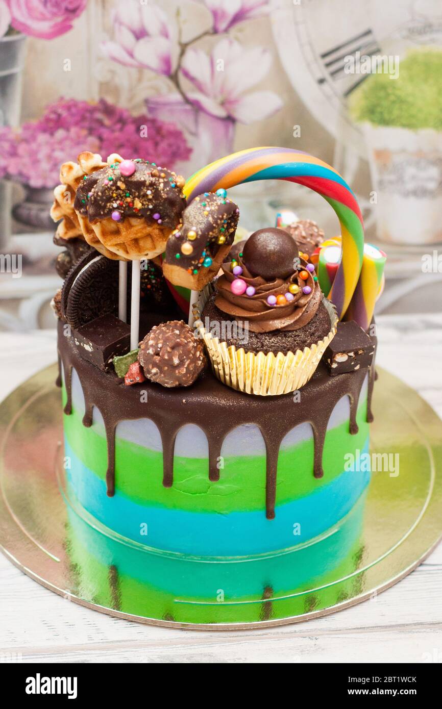 Pastel azul y verde decorado con chocolate fundido, paletas de pastel,  paletas de lollipops, donuts y mini cupcakes Fotografía de stock - Alamy